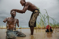 دستان اين مرد بخاطر حمله يك شير به پناهگاه حيات وحش سلوس در تانزانيا، جائيكه روستائيان فقير در كنار آن به كشاورزي مشغول هستند، قطع شد. عموي او در حال استحمام اوست.
